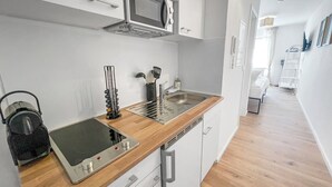 Une cuisine moderne équipée d’un four à micro-ondes, d’une cuisinière et d’un évier. On y trouve des placards et un plan de travail en bois.