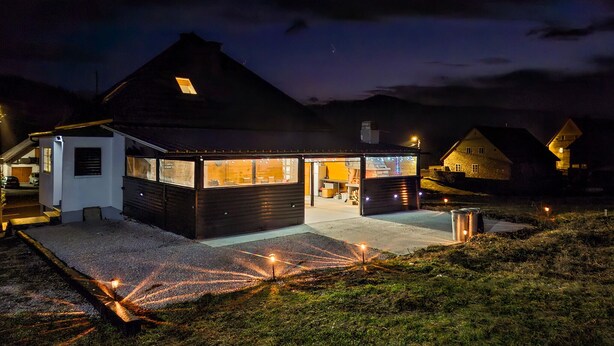 Una casa moderna amb un teulat inclinat, un petit porxo i un interior ben il·luminat.