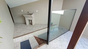 A modern bathroom with a sink, a glass shower enclosure, and a small step leading to the shower area. - Hospedaria Estadia Do Vale  (União da Vitória)