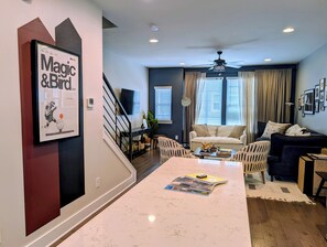 A modern living room with a marble coffee table, a sofa, and a television. - Rooftop Retreat: 3BR/3.5BA, garage, pet friendly, sleeps 8, walk to Uptown (Charlotte)
