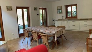 A dining area with a table and chairs, a kitchen with white cabinets, and a window. - Sopri House - Relaxation and Lake View, Private Garden and Veranda (Malcesine)