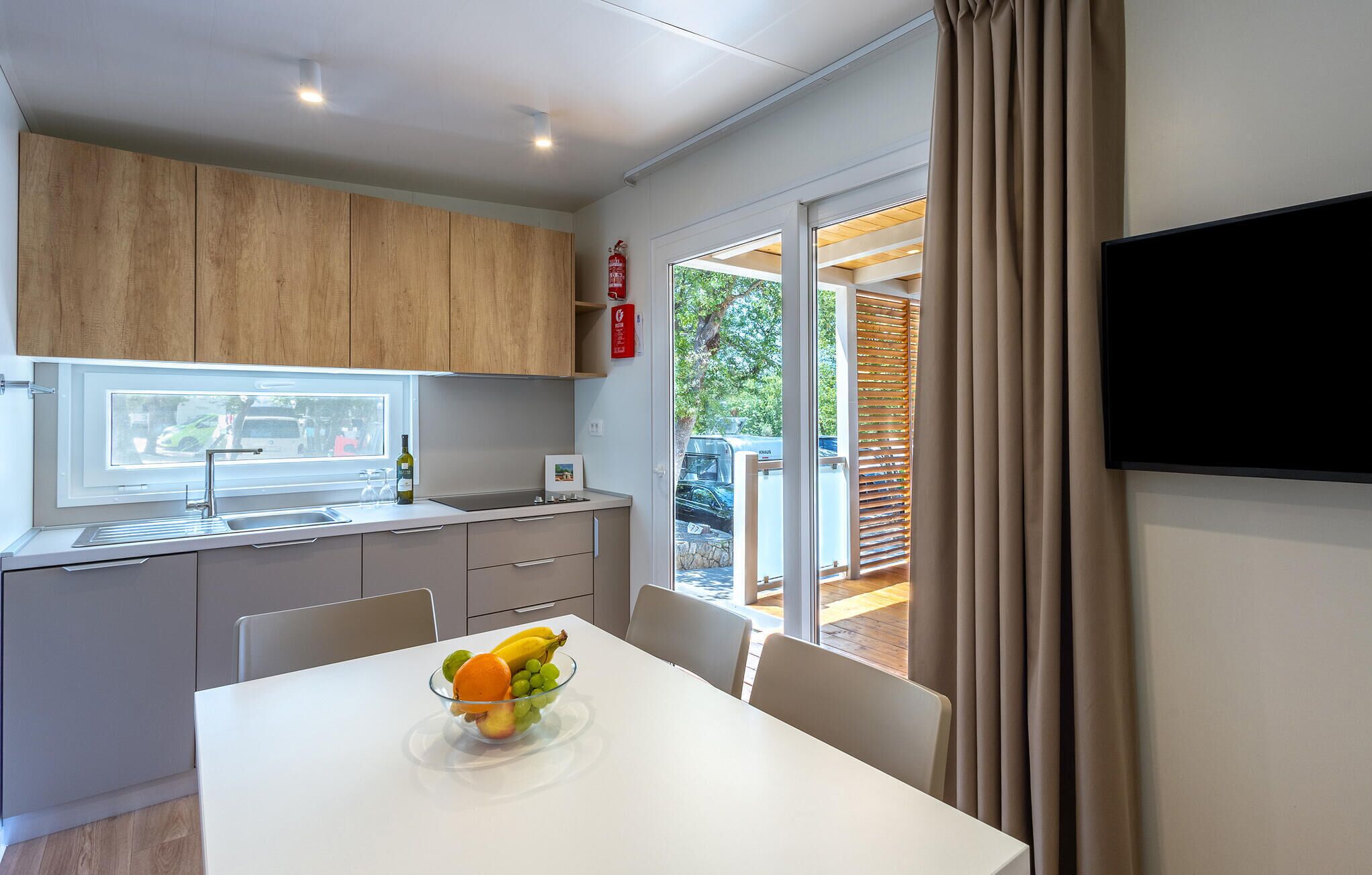 Une cuisine moderne avec des meubles en bois, une fenêtre donnant sur l’extérieur et un coin repas agrémenté d’un panier de fruits.