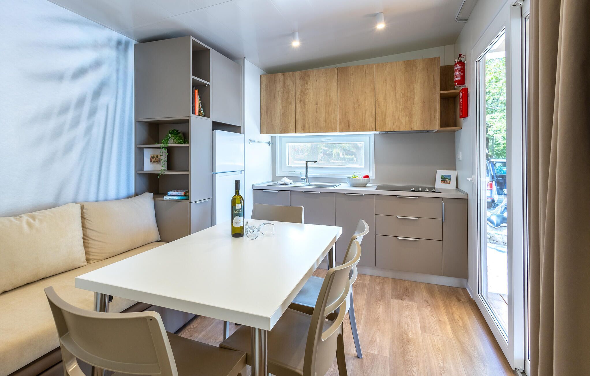 A compact kitchen with a dining area, wooden cabinets, and a window with a view.