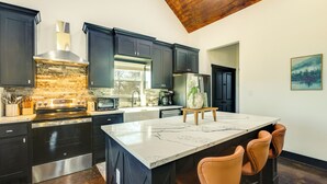 Een moderne keuken met donkere kastjes, een groot eiland en een houten plafond.