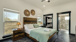 Quarto com cama, mesas de cabeceira, ventilador de teto e vista para o exterior.