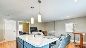 Une cuisine moderne dotée d’un îlot central, d’appareils électroménagers intégrés et d’un coin salon avec un canapé et des fauteuils.