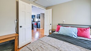 Une chambre à coucher avec un lit, des tables de chevet et une porte ouverte donnant sur une cuisine.