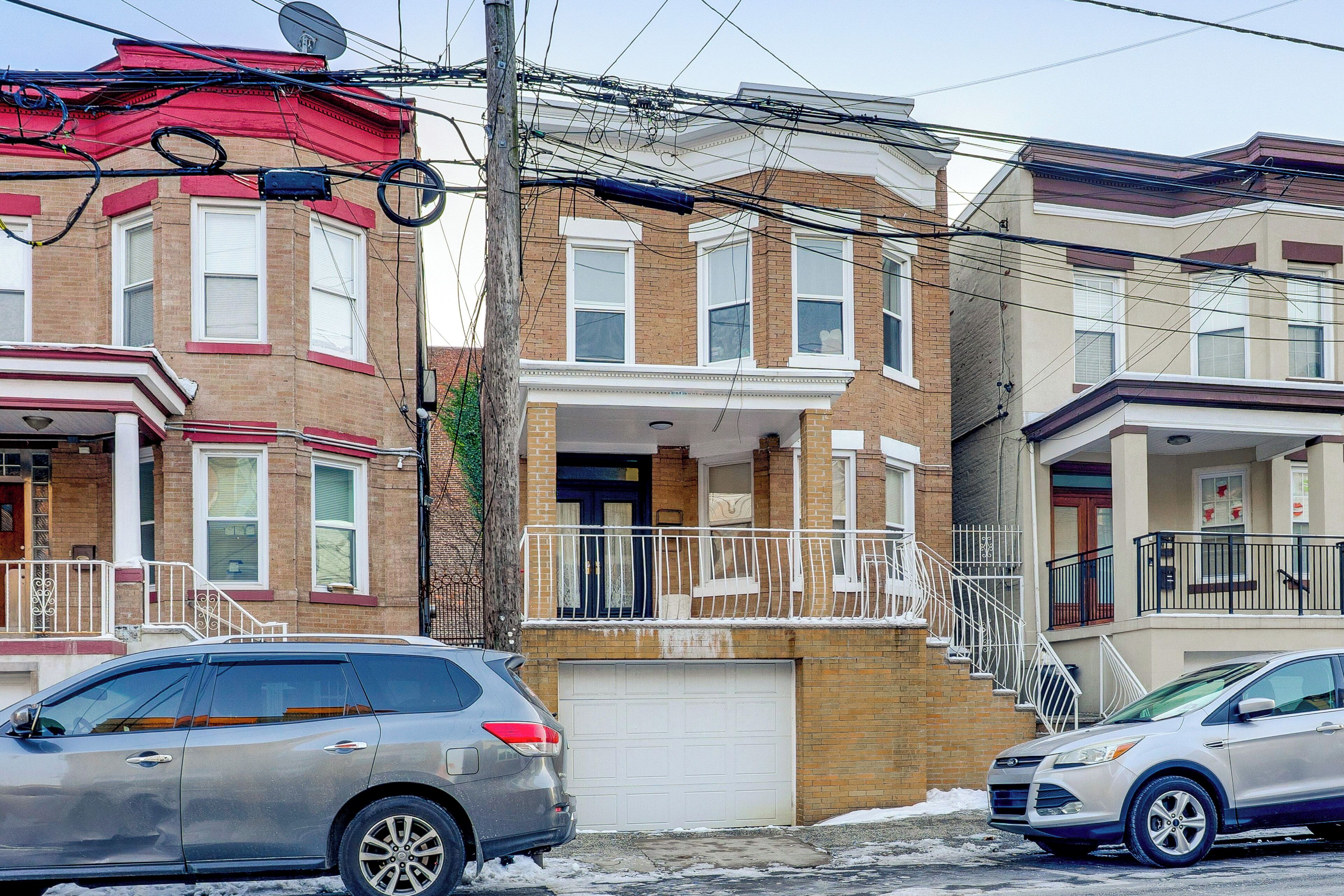 A row of brick townhouses with a garage, a satellite dish, and a utility pole with multiple wires.