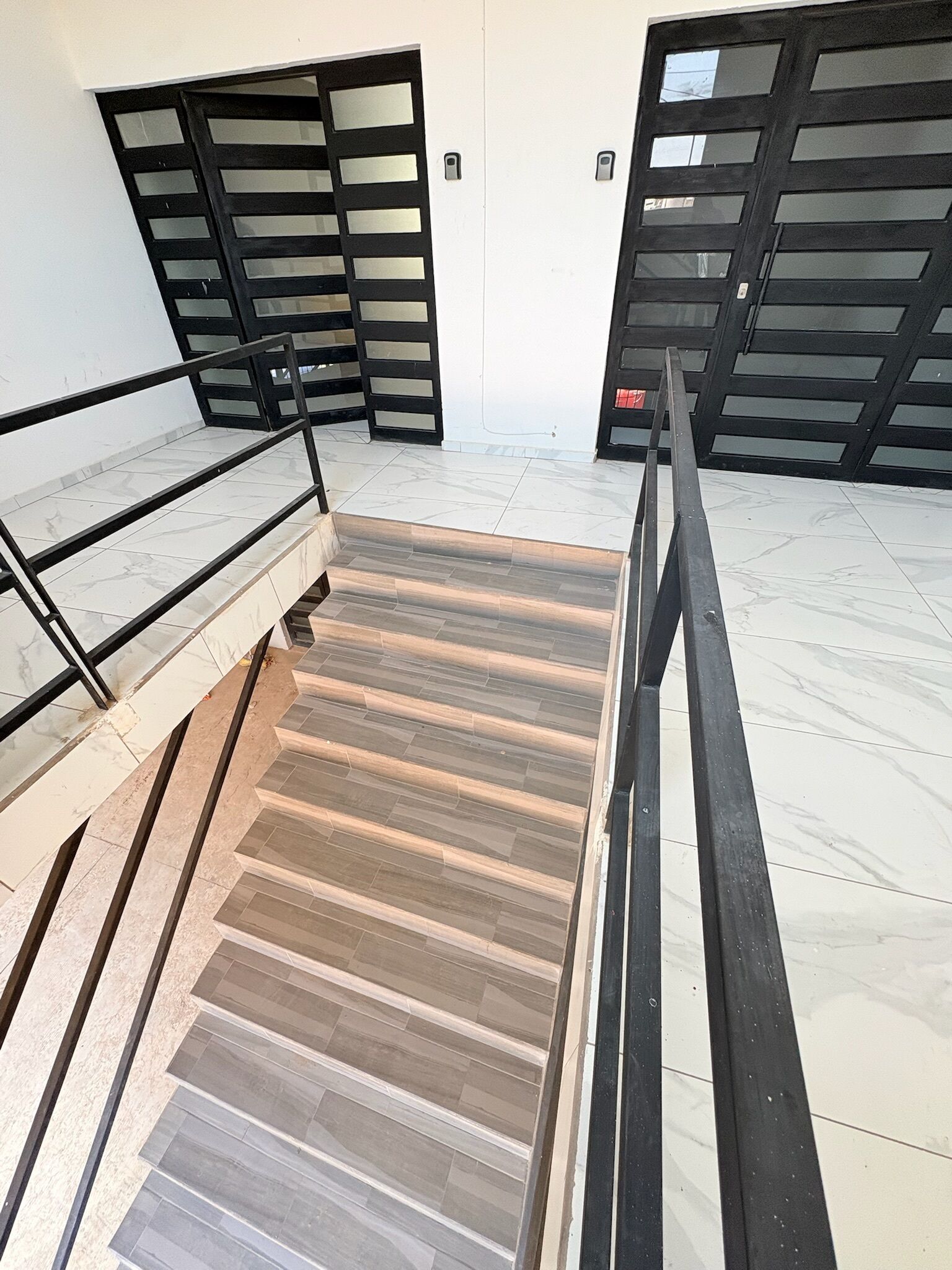 Un escalier avec une rampe métallique menant à un palier.