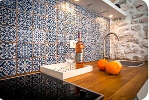 Eine Küche mit blauen und weißen Fliesen, einer Olivenölflasche, zwei Orangen und einem Spülbecken.