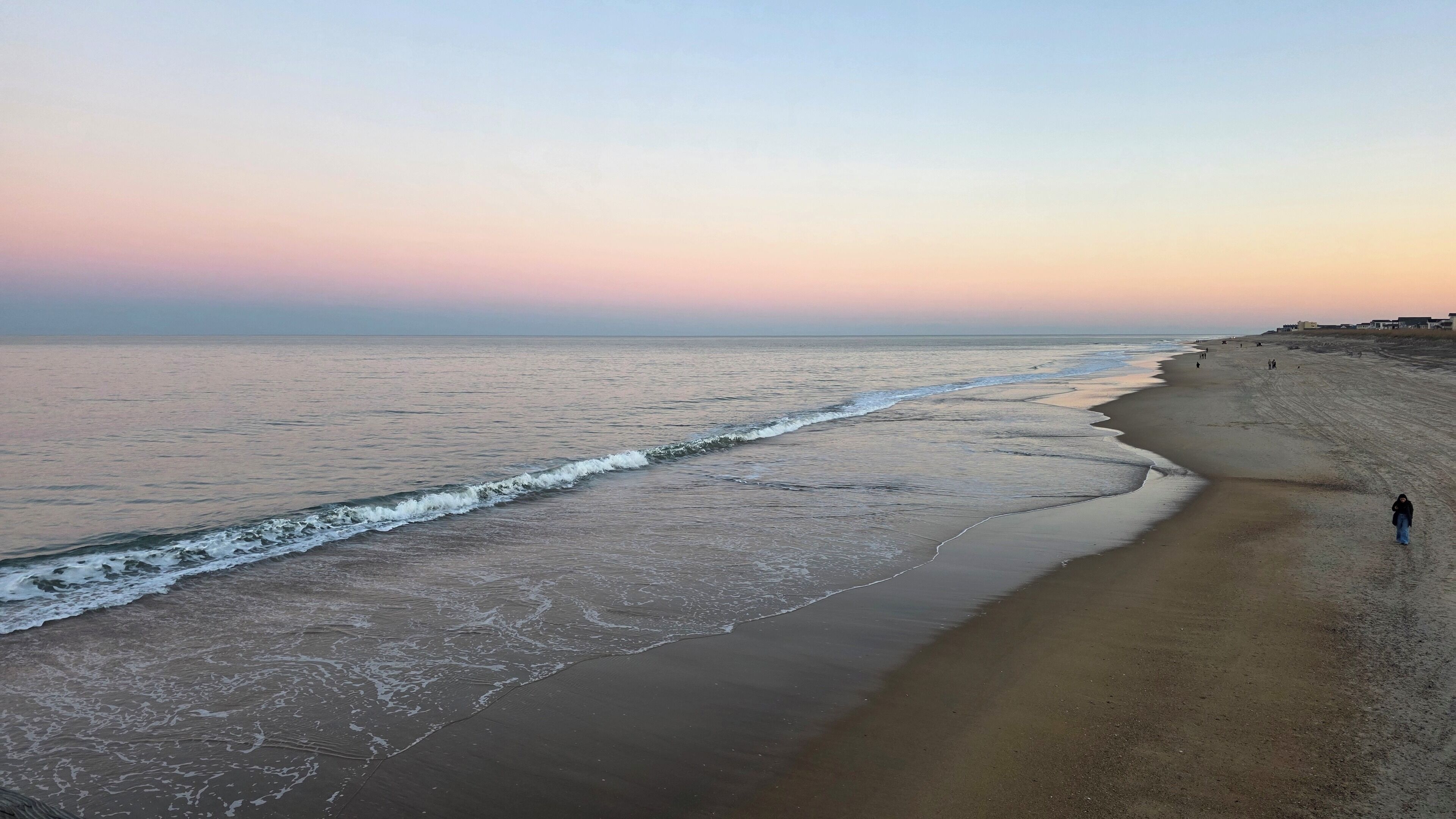 Une plage où une personne se promène le long du rivage.