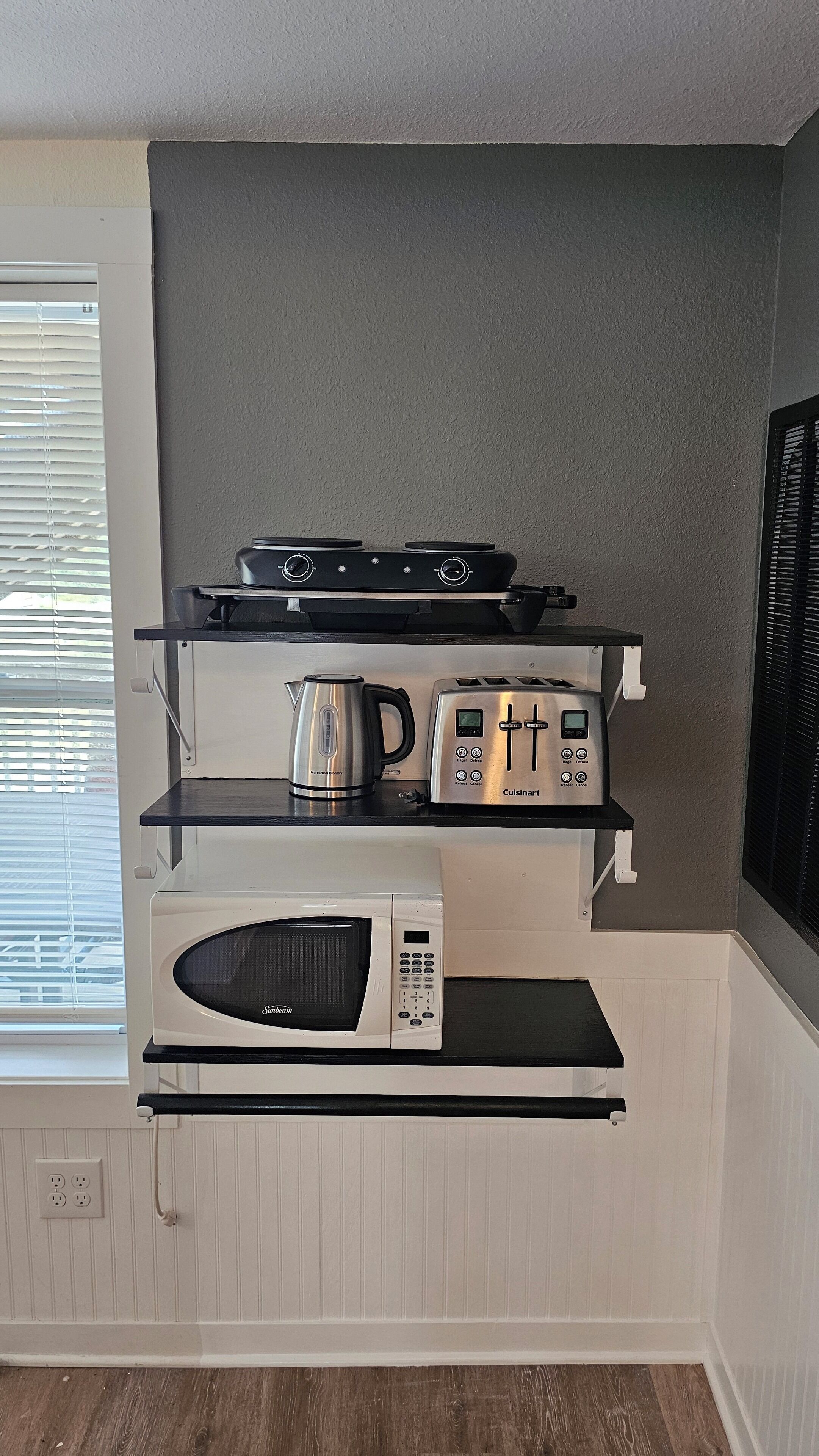 Eine Küche mit Mikrowelle, Toaster, Wasserkocher und Herd auf einer weißen Arbeitsfläche.