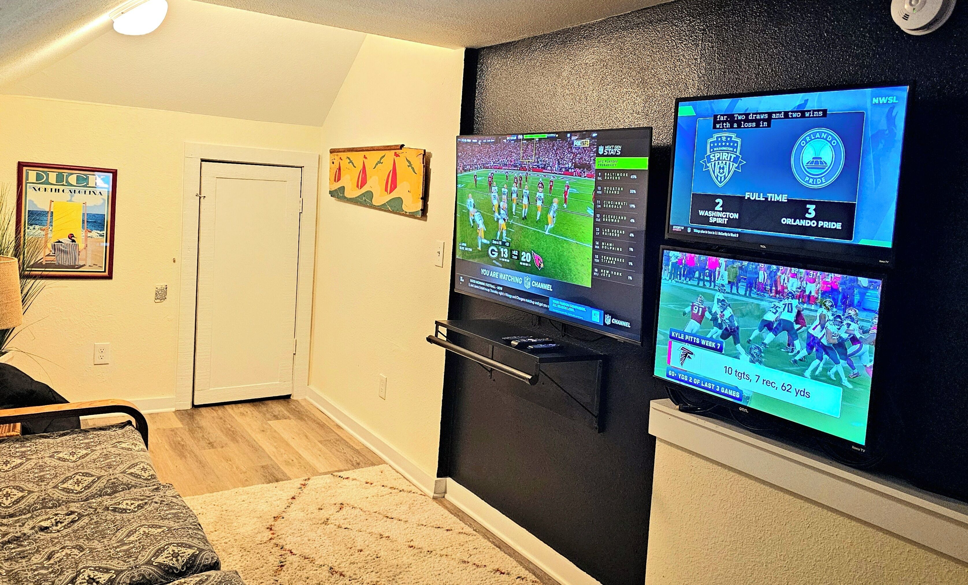 Ein Wohnzimmer mit einem Flachbildfernseher an einer schwarzen Wand, der ein Fußballspiel zeigt.
