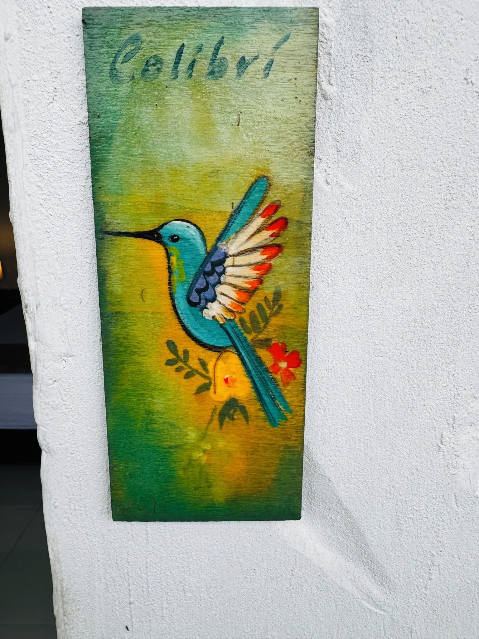 Un mural de un colibrí sobre una pared con textura.