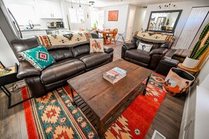 Een moderne woonkamer met een leren bank, een houten salontafel en een rood tapijt met een patroon.