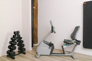 A home gym setup with an elliptical machine, a set of dumbbells, and a yoga mat.