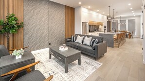 Ett modernt vardagsrum med en grå soffa, ett soffbord och detaljer i trä.