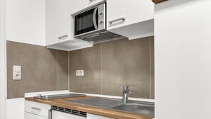 Une cuisine moderne équipée d’un four à micro-ondes, d’un évier et d’un plan de travail en bois.