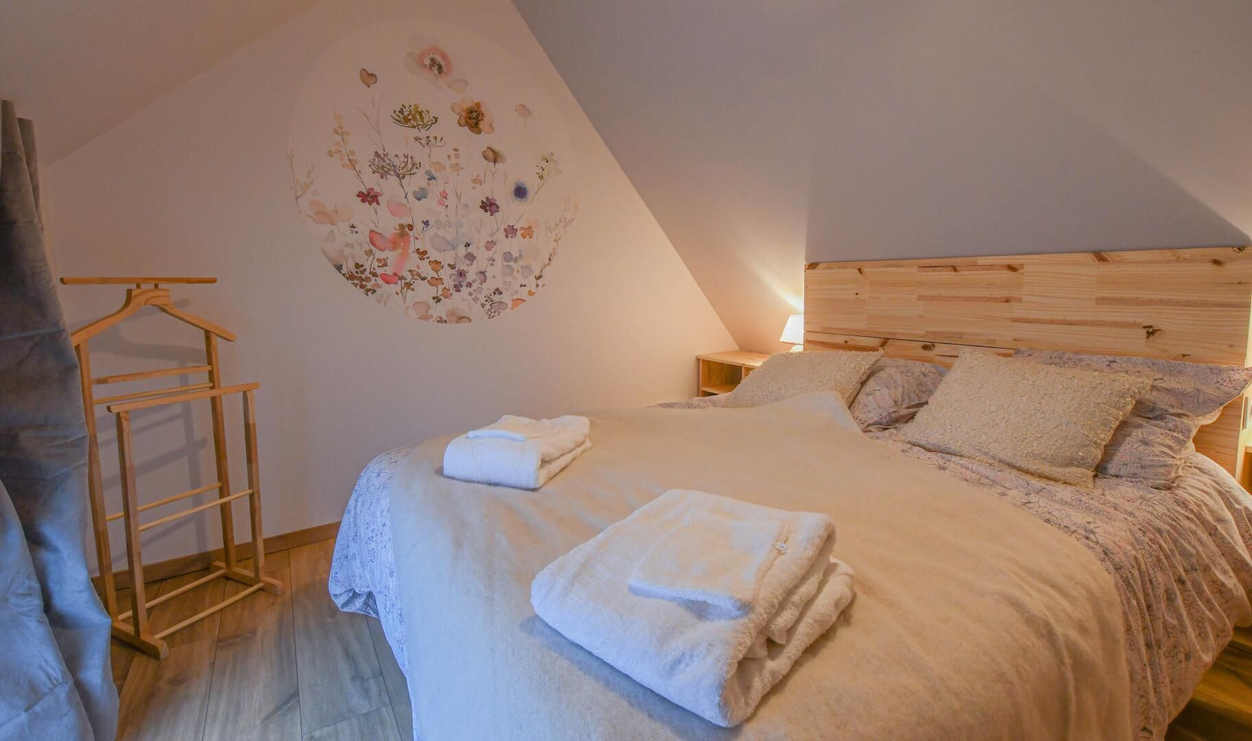 Une chambre à coucher avec une tête de lit en bois, un lit recouvert de draps blancs, une échelle en bois et un élément décoratif mural.