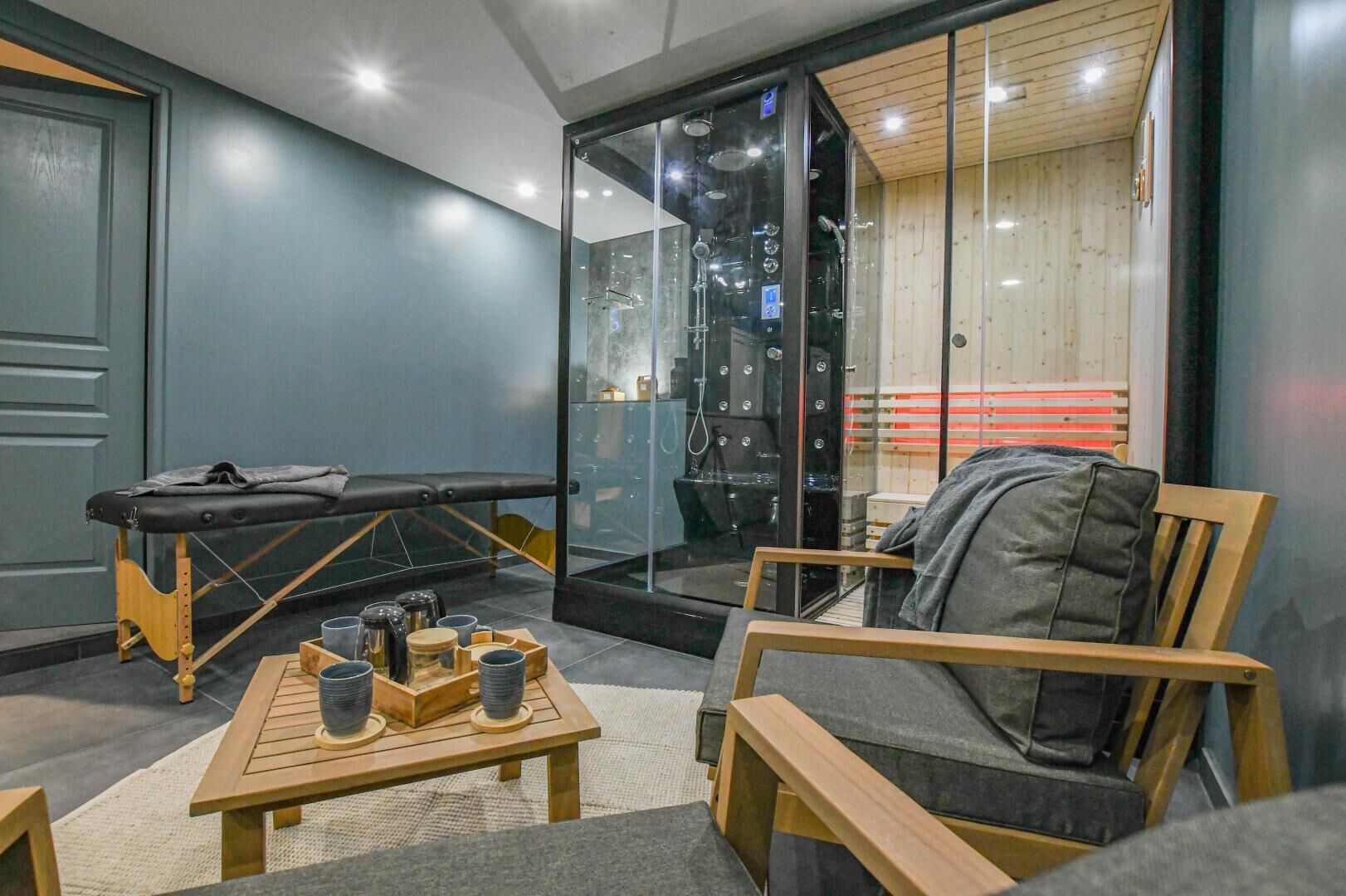 A massage therapy room with a wooden table, massage table, and a chair.