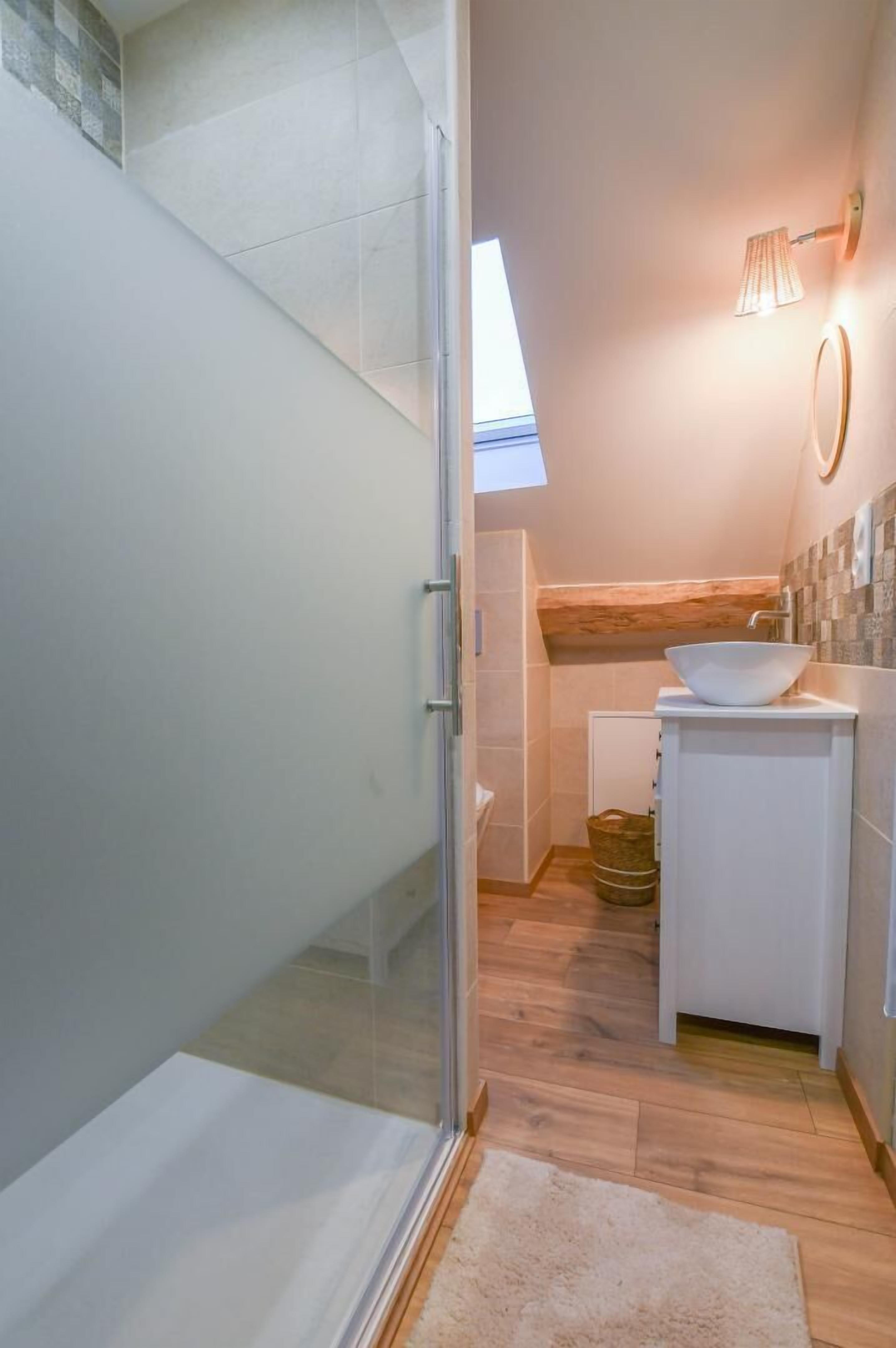 Un baño moderno con ducha de vidrio, lavamanos blanco y techo de madera.