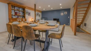 Un comedor con una mesa redonda, seis sillas y un aparador de madera con cristalería.