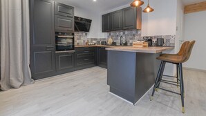 Una cocina moderna con armarios oscuros, una isla central e iluminación colgante.