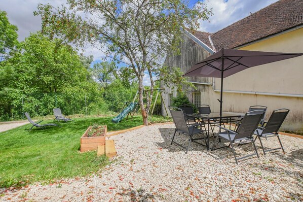 A patio with a table and chairs, a swing set, and a slide.