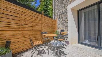 A patio with a wooden fence, a table with chairs, and a stone wall.