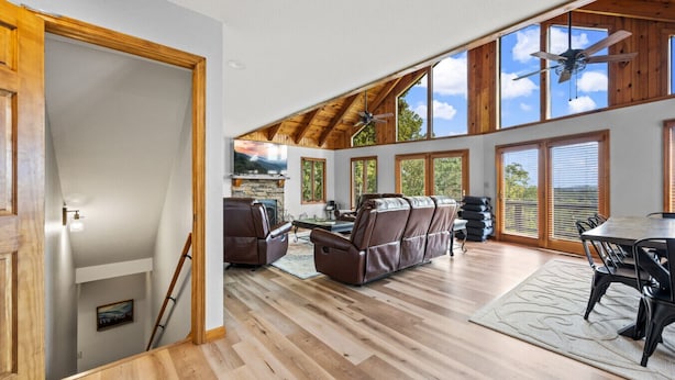 A spacious living area with a fireplace, leather sofa, and a dining table with chairs. - High Top: AMAZING views on a private 100 acres within city limits: EXCLUSIVE! (Sevierville)