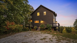 A two-story house with a dark exterior, a front porch, and a gravel driveway. - High Top: AMAZING views on a private 100 acres within city limits: EXCLUSIVE! (Sevierville)