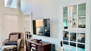 Een woonkamer met een televisie, een bank, een bijzettafeltje en een boekenkast.
