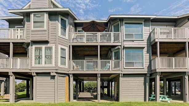 Een meerlaags huis met een balkon, een overdekte veranda en een patio.