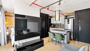A modern living room with a flat-screen TV, a sofa, and a dining area with chairs. - 1811 Mercure (São Paulo)