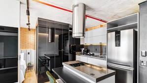 A modern kitchen with a built-in stove, stainless steel appliances, and a compact dining area. - 1811 Mercure (São Paulo)