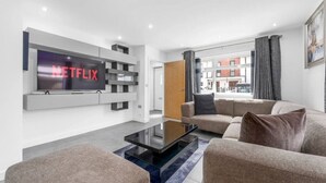 Una sala de estar moderna con un televisor de pantalla plana montado en la pared, una mesa de centro y dos sofás.