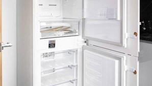 Un refrigerador abierto con varios estantes y un compartimento congelador.
