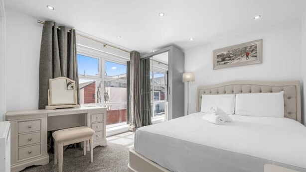 Un dormitorio con cama, escritorio, silla y ventana.
