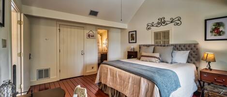 A bedroom with a bed, a ceiling fan, a nightstand, a lamp, a dresser, and a door leading to another room.