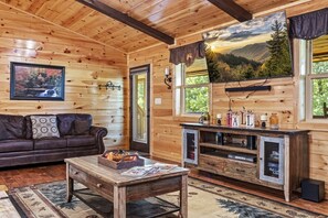 Ein gemütliches Blockhaus-Interieur mit Holzausstattung, einer Couch, einem Couchtisch und einem Fernseher.