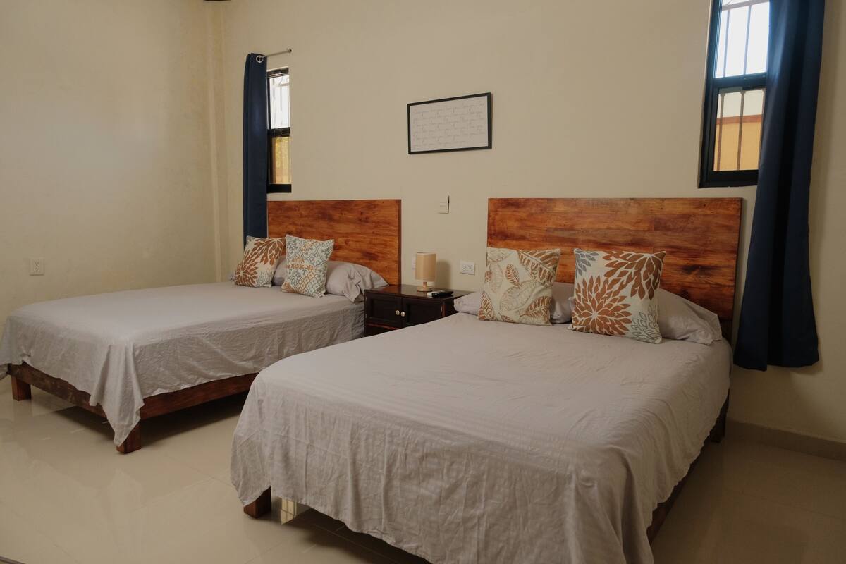 Two single beds with wooden headboards, a small bedside table, and a framed inspirational quote on the wall.