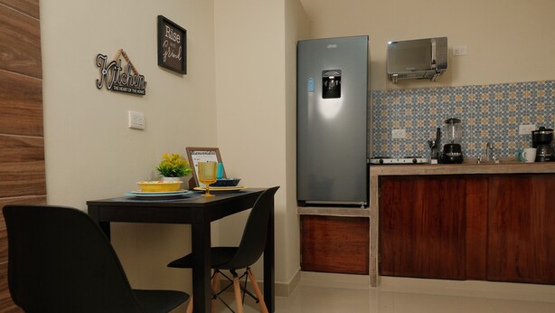 A compact kitchen with a refrigerator, microwave, and coffee maker. There is a small dining table with two chairs. - Hanna suite  (Catemaco)