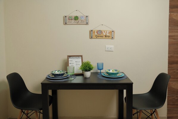A dining table with two chairs, a menu, a potted plant, and decorative signs on the wall. - Hanna suite (Catemaco)