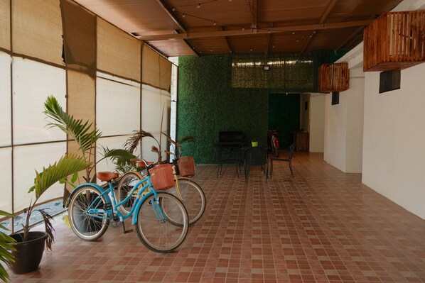 Ein überdachter Patio-Bereich mit Fliesenboden, einem blauen Fahrrad und Topfpflanzen.