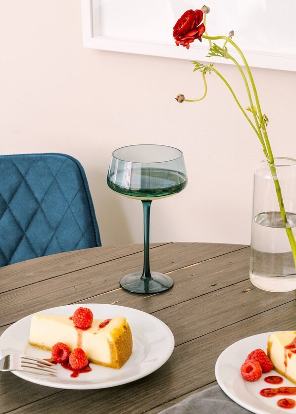 A dining table with a plate of cheesecake and raspberries, a glass of water, and a vase with a single red rose. - LIVN - Millennium Park Downtown Chicago (Chicago)