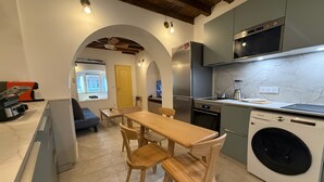 A compact kitchen with a dining area, a washing machine, and a view into the living area. - A jewel in TOULOUSE (Toulouse)