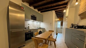 A compact kitchen with a refrigerator, oven, and sink. There is a dining table with chairs. The kitchen has a tiled floor and a wooden ceiling. - A jewel in TOULOUSE (Toulouse)