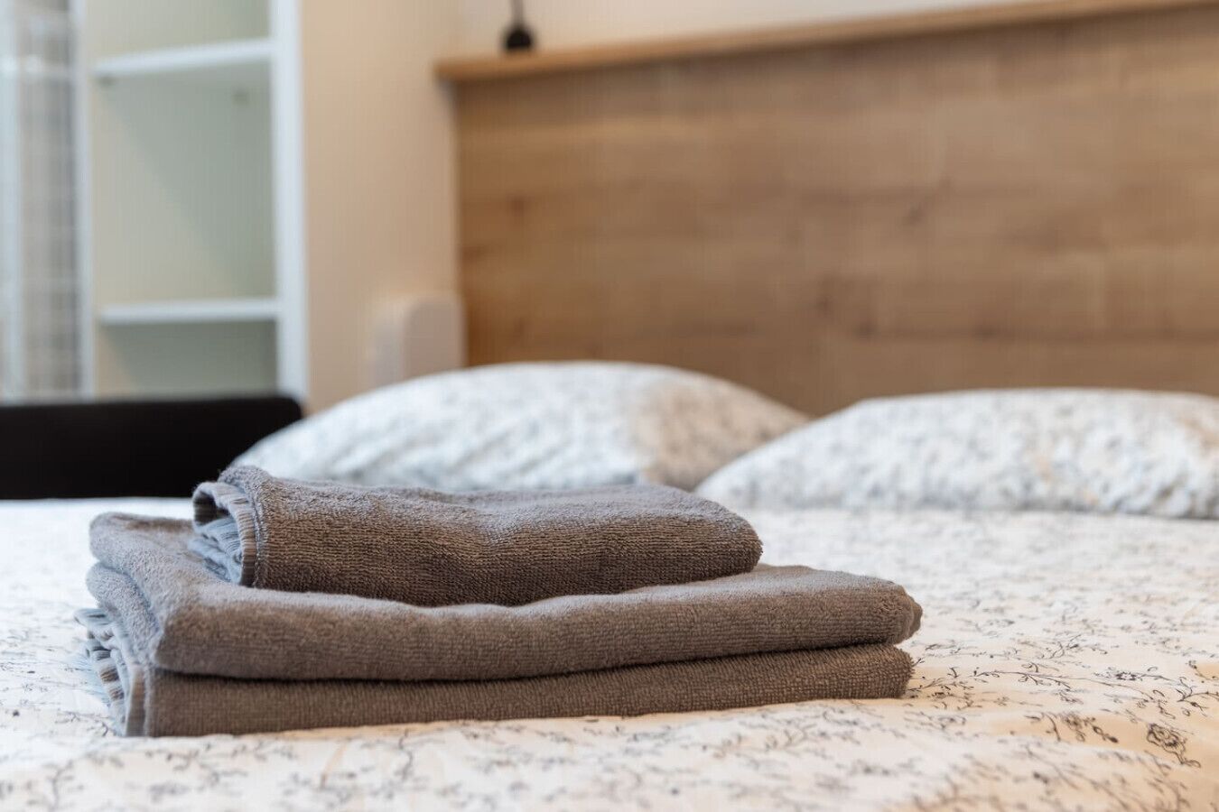 Un lit bien fait, avec des serviettes pliées et une tête de lit en bois.
