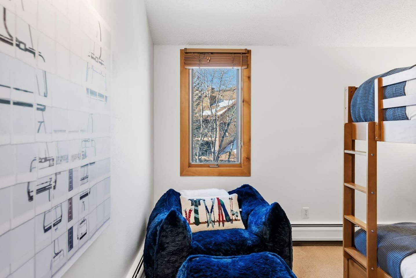A room with a bunk bed, a window with a view of trees, and a wall with architectural drawings.