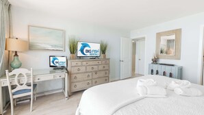 Ein Hotelzimmer mit einem Bett, einem Schreibtisch, einer Kommode, einem Fernseher und einem gerahmten Bild an der Wand.